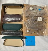 Overall view of box showing eyeglass frames in plastic sleeves and cases