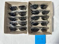 Two trays holding twelve individually wrapped black lens silver frame sunglasses