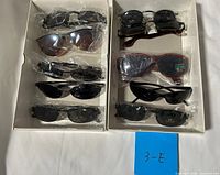 Two open boxes showing nine pairs of sunglasses in plastic sleeves