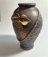 Full view of bronze ceramic vase with gold lily applique