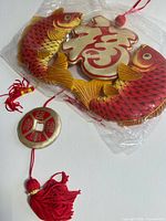 Front view of wall hanging with fish, Fu character, coin and tassel