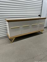 Front view of white console with wood trim and gold hardware