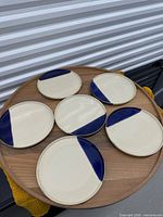 Six plates arranged on tabletop showing top surfaces