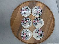 set of six floral plates arranged on wood surface