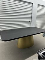 Full view of table showing black top and gold pedestal base