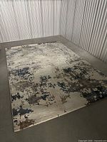 Full view of rug laid flat displaying abstract design and approximate dimensions
