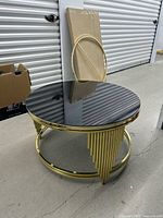 Angled view showing full table, gold rod base, black glass top