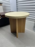 Full view of side table showing round stone top and wood pedestal base