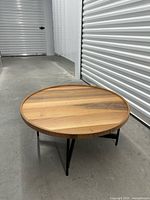 Full view angled of round wood table, shows top surface and legs