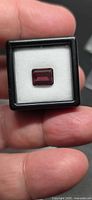 Front view of emerald-cut rubellite set in display box