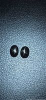 Pair of black star diopside cabochons on textured background