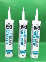 Three sealed DAP Alex Plus caulk tubes front view