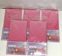 Five sealed pink ombre Spritz table cover packages arrayed