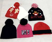 All six beanies laid out showing colors, designs and pom-poms