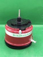 Front view of red KitchenAid motor base showing logo and spindle