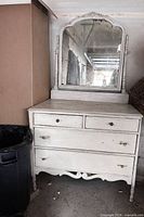 Front view of white wooden vanity dresser showing four drawers and attached mirror