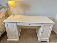 Front view of white desk with lamp on top