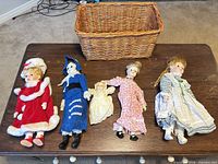 Group shot of all five dolls on table with wicker basket