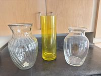 Front view of three vases: clear ribbed, yellow cylinder, clear bulbous