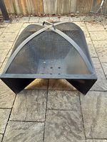 Overall view of black steel square fire pit with arched mesh lid