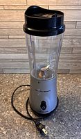 Front view of assembled blender showing silver base, clear jar, black lid and power cord