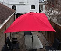 Top-down view of red rectangular umbrella covering patio table