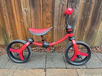 Left side view of red balance bike showing frame, seat, wheels and condition