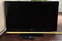 Front view of Sony BRAVIA 40-inch TV with remote and measuring tape