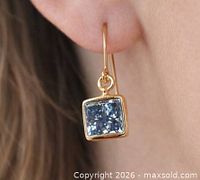 Earring on ear showing size, drop style, blue diamond in gold bezel