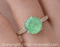 Ring on finger displaying emerald and accent stones