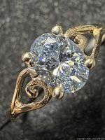 Close-up of oval lab diamond and gold scrollwork band