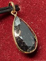 Front view of pear-shape black diamond pendant on red background