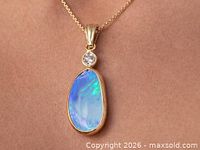 Front view of gold pendant on chain showing opal and diamond