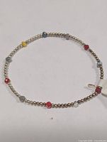 Bracelet laid flat showing gold-tone beads with coloured accents