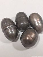 Four dark grey barrel-shaped pearls grouped