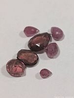 Seven loose faceted garnet stones on white background