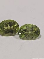 Close-up of two oval peridot gemstones showing color, cut and clarity