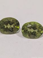 Close-up of two oval peridot gemstones showing facets and color