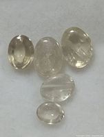 Five oval cabochon gemstones on white background