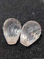 Two faceted pear-shape rose quartz stones on black background