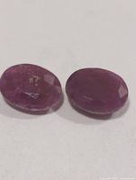 Two oval faceted rubies on white background