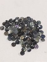 Pile of small round faceted sapphires on white background