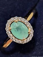 Front view of ring showing oval green stone and halo