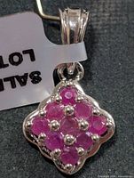 Front view of silver pendant with nine rubies and bail