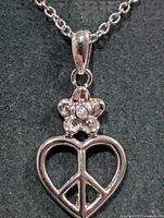 Close-up of pendant showing peace heart and flower with diamond