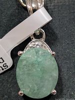 Front view of sterling silver pendant with oval dyed emerald and accent stones