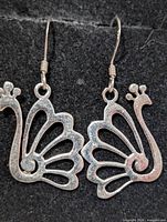 Front view of both silver peacock earrings showing design and hooks