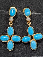 Front view of both earrings showing turquoise cabochons and pearl accents
