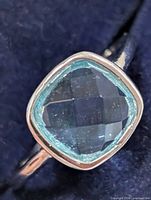 Front angled view highlighting cushion-cut blue topaz and bezel mount