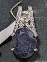 Front view showing oval sapphire and silver bail with accent stones
